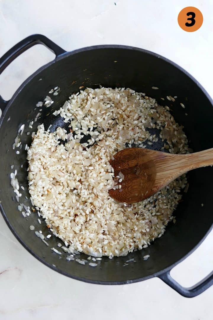 arborio rice and shallots in a dutch oven on a white counter