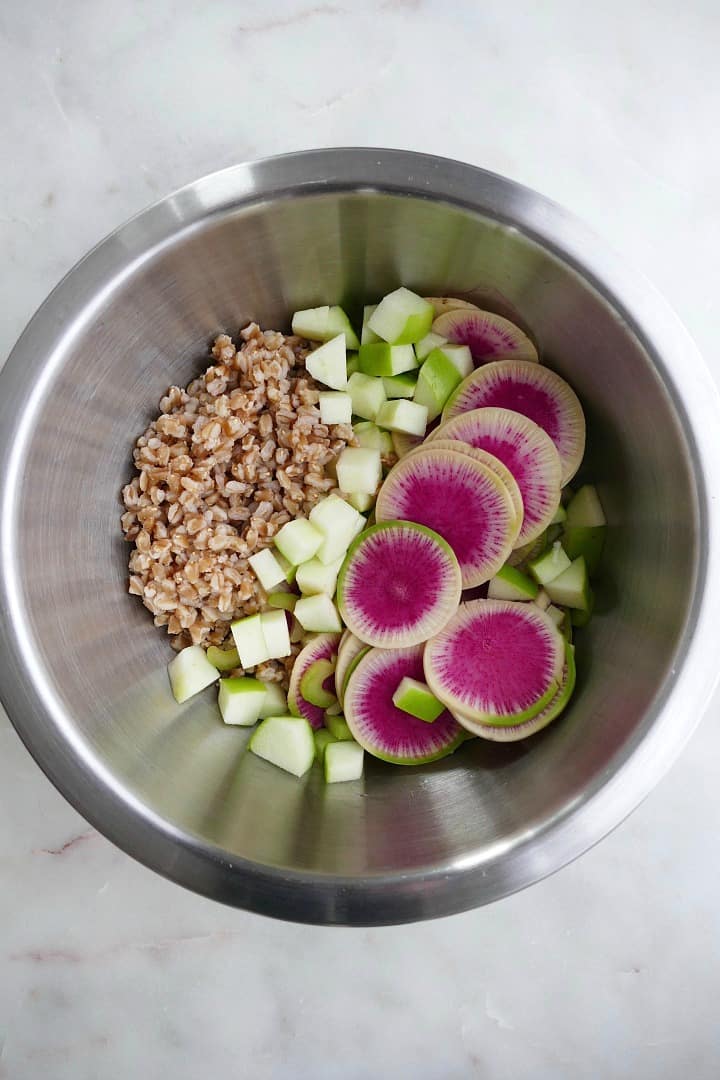farro, granny smith apple, celery, and watermelon radishes in a metal mixing bowl