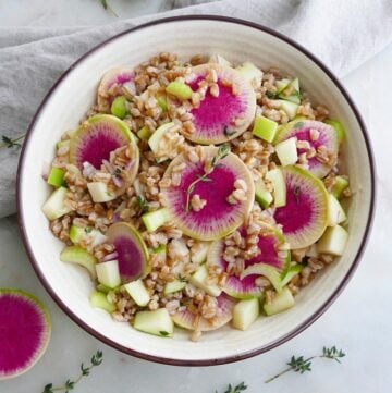 watermelon radish salad with thyme in a white bowl on a counter