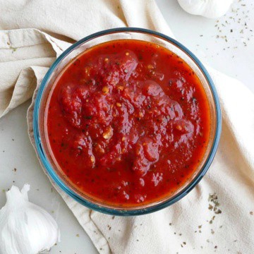 close up of san marzano tomato sauce in a glass container on a yellow napkin