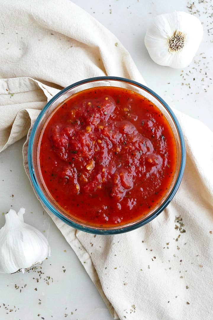 close up of san marzano tomato sauce in a glass container on a yellow napkin