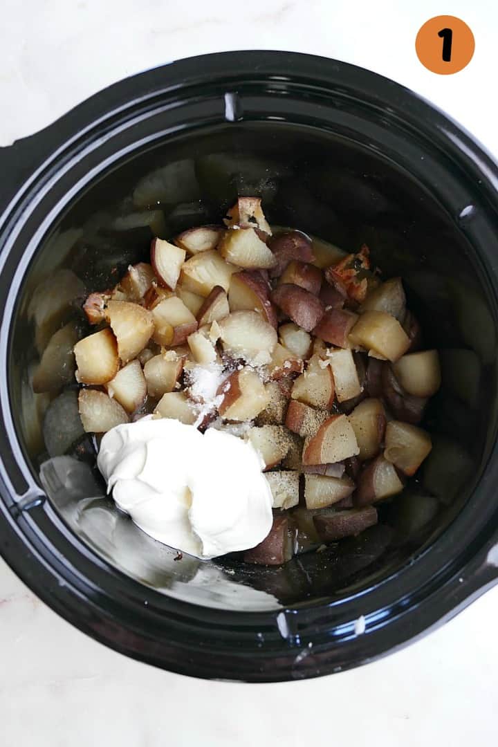 diced potatoes with a dollop of sour cream in a black slow cooker