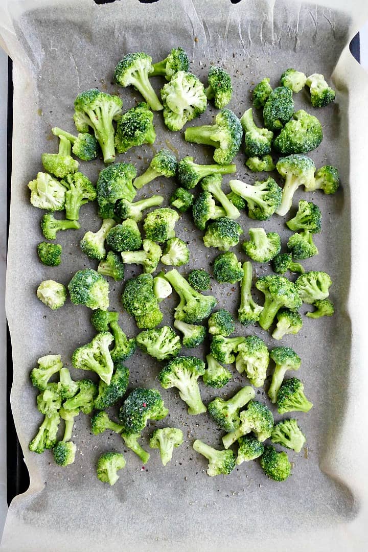 baking sheet lined with parchment paper with a single layer of broccoli florets
