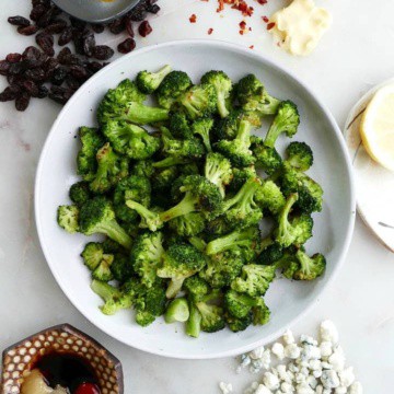 plate of the roasted frozen broccoli in the middle of five different seasoning combos