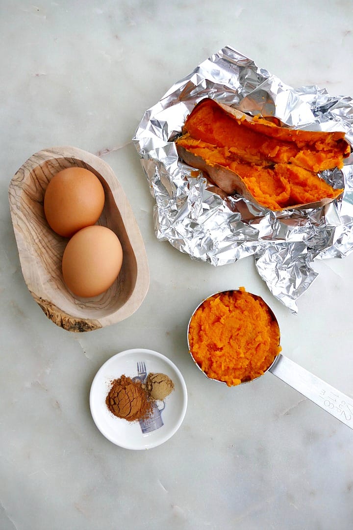 baked sweet potato in foil and a measuring cup, 2 eggs, and spices
