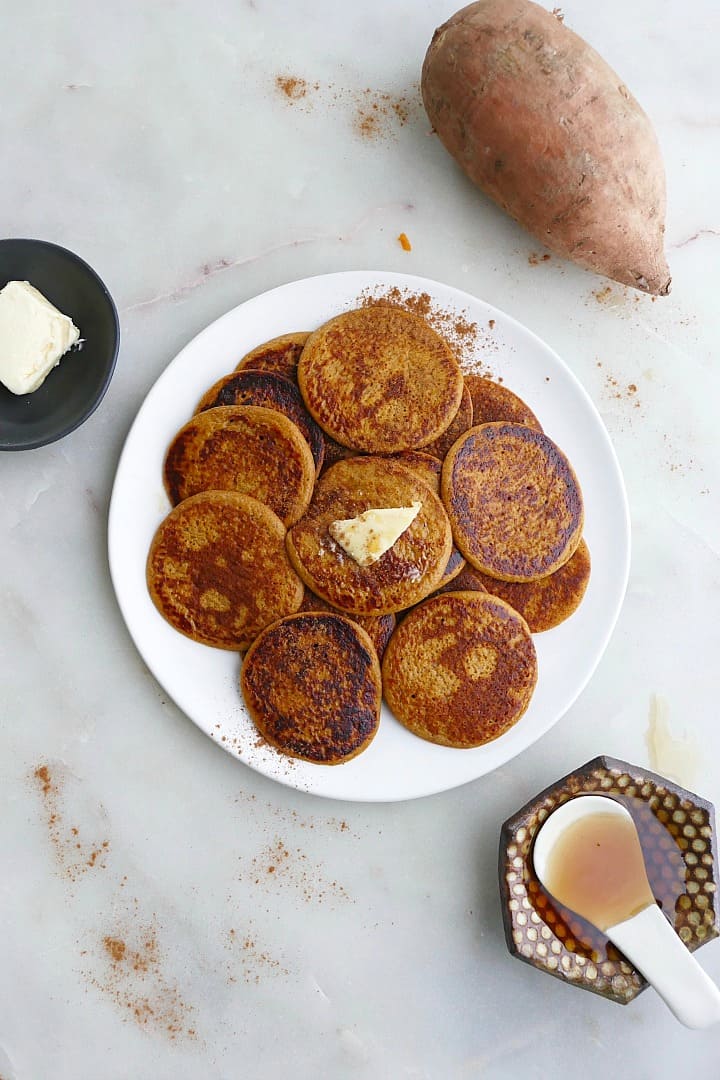 pile of silver dollar sweet potato pancakes on a white plate on a counter