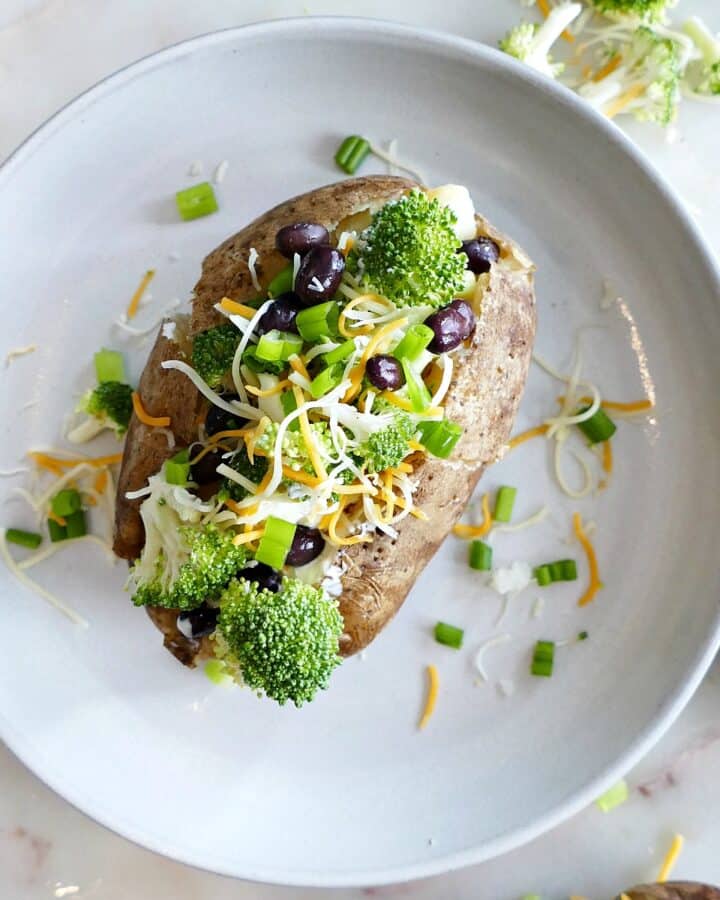 square image of a baked potato with toppings on a white plate
