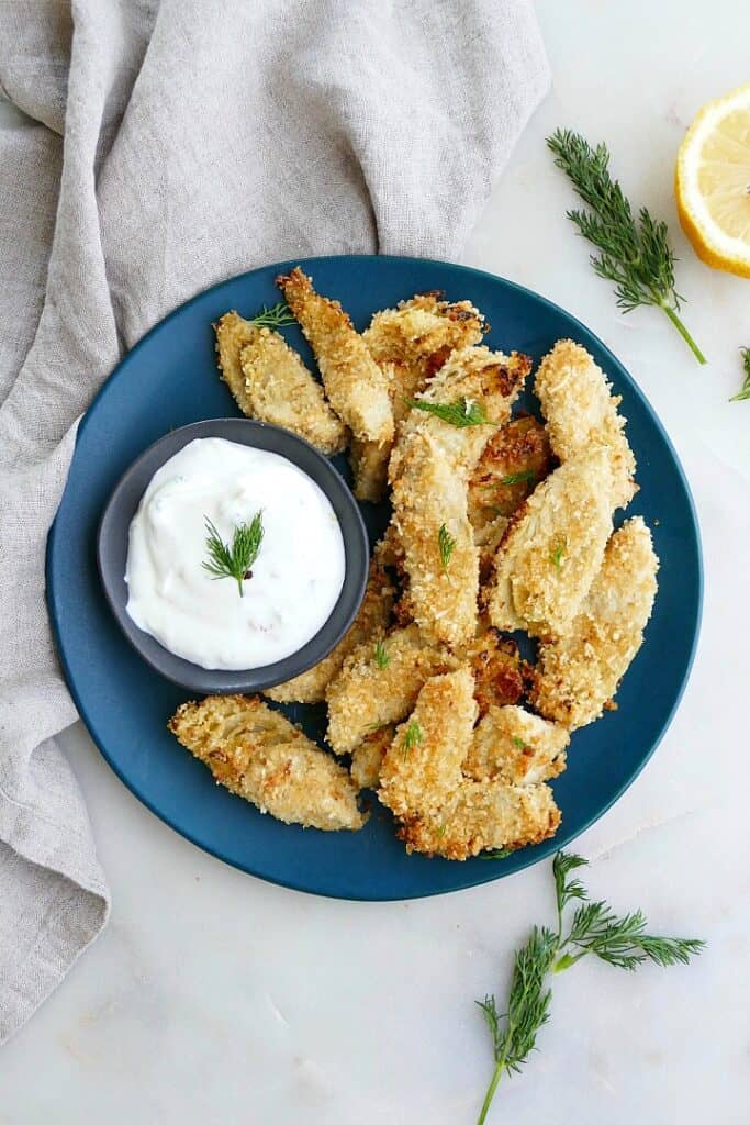 crispy artichoke hearts with aioli on a blue plate on top of a counter