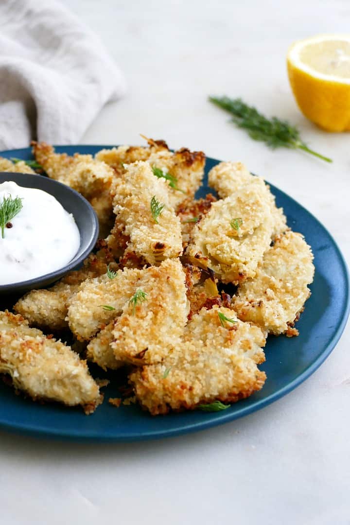 side view of crispy artichoke hearts on a blue plate with white background