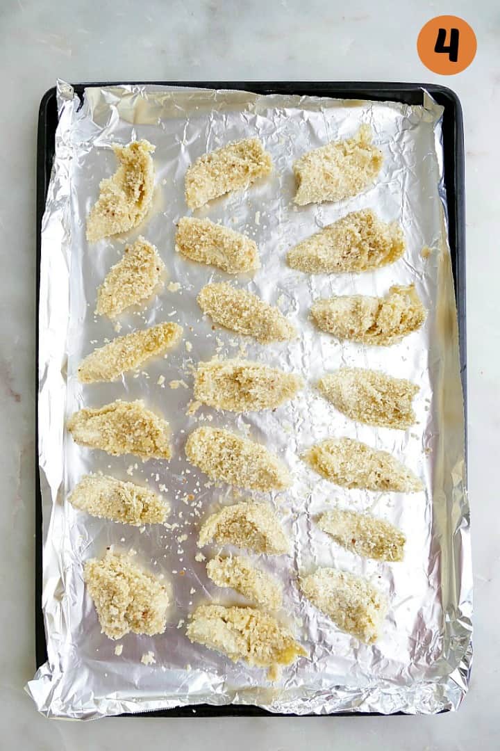 coated artichoke hearts in three layers on a baking sheet with foil