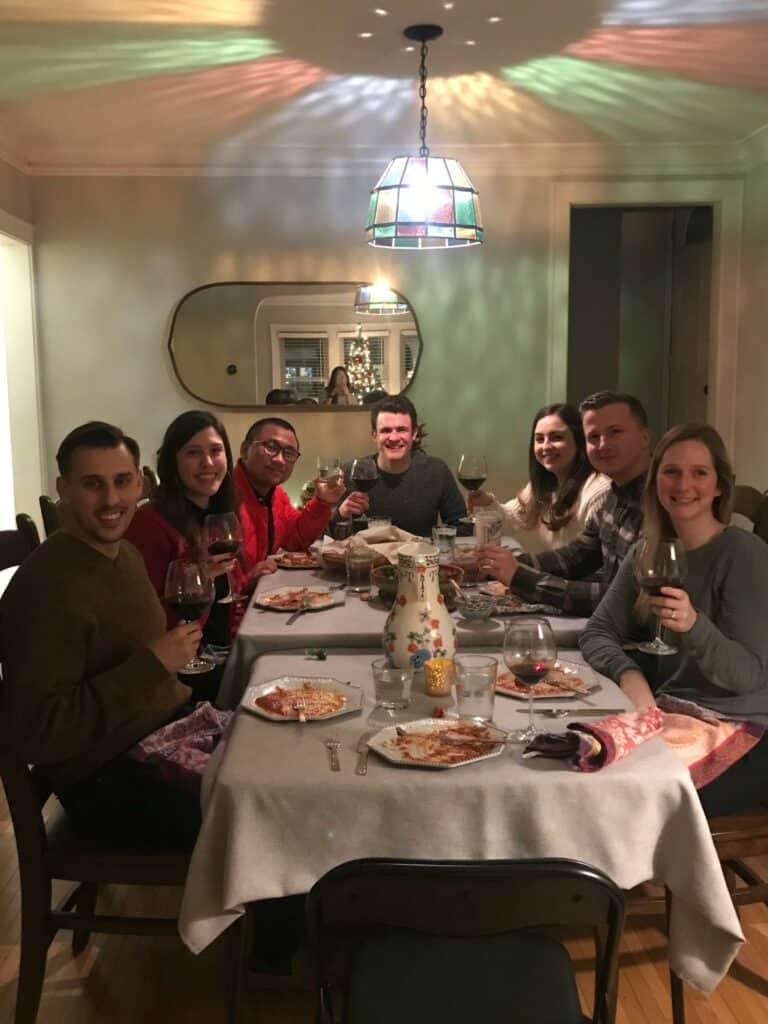 7 friends sitting around a table drinking wine and smiling