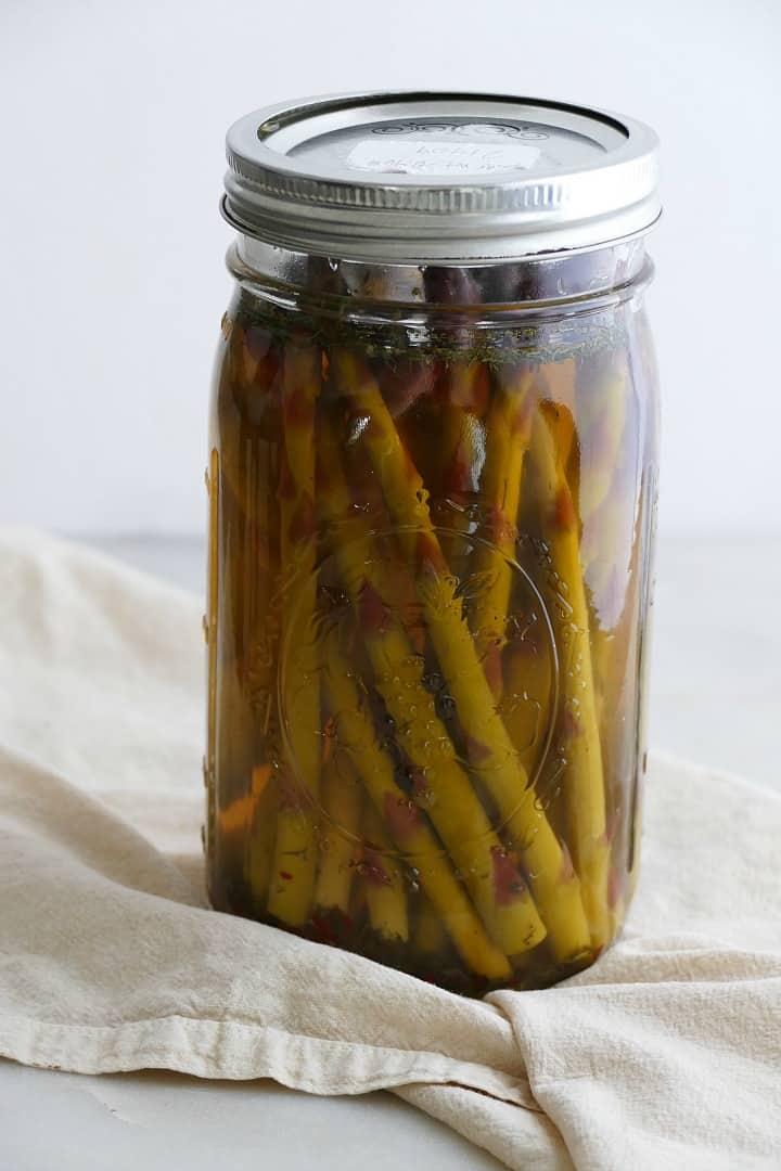 side view of pickled asparagus upright in a quart-sized glass mason jar
