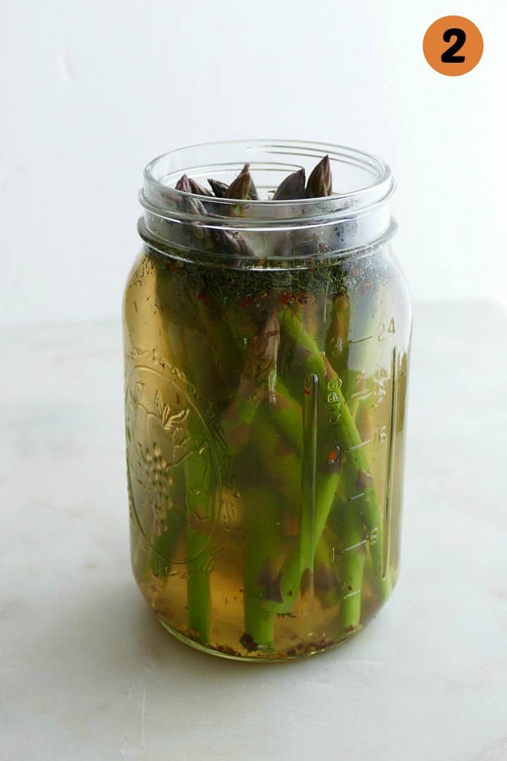 asparagus spears in pickle brine in a glass quart mason jar