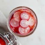 overhead of a glass jar of pickled radishes on a white counter