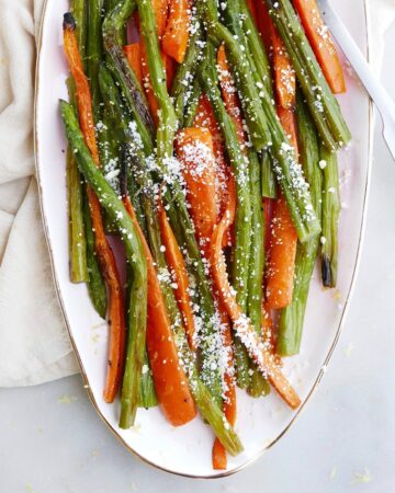 square image of roasted asparagus and carrots on a pink oval tray