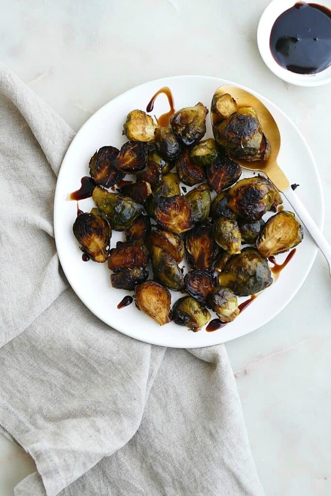 roasted frozen brussels sprouts drizzled with balsamic reduction on a white plate