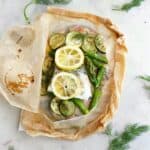 cod en papillote with lemon slices and green vegetables on a white counter