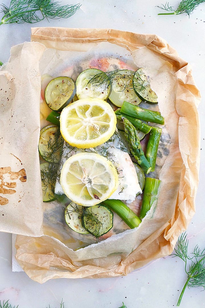 close up of cod en papillote with fresh lemon slices and dill in a parchment packet