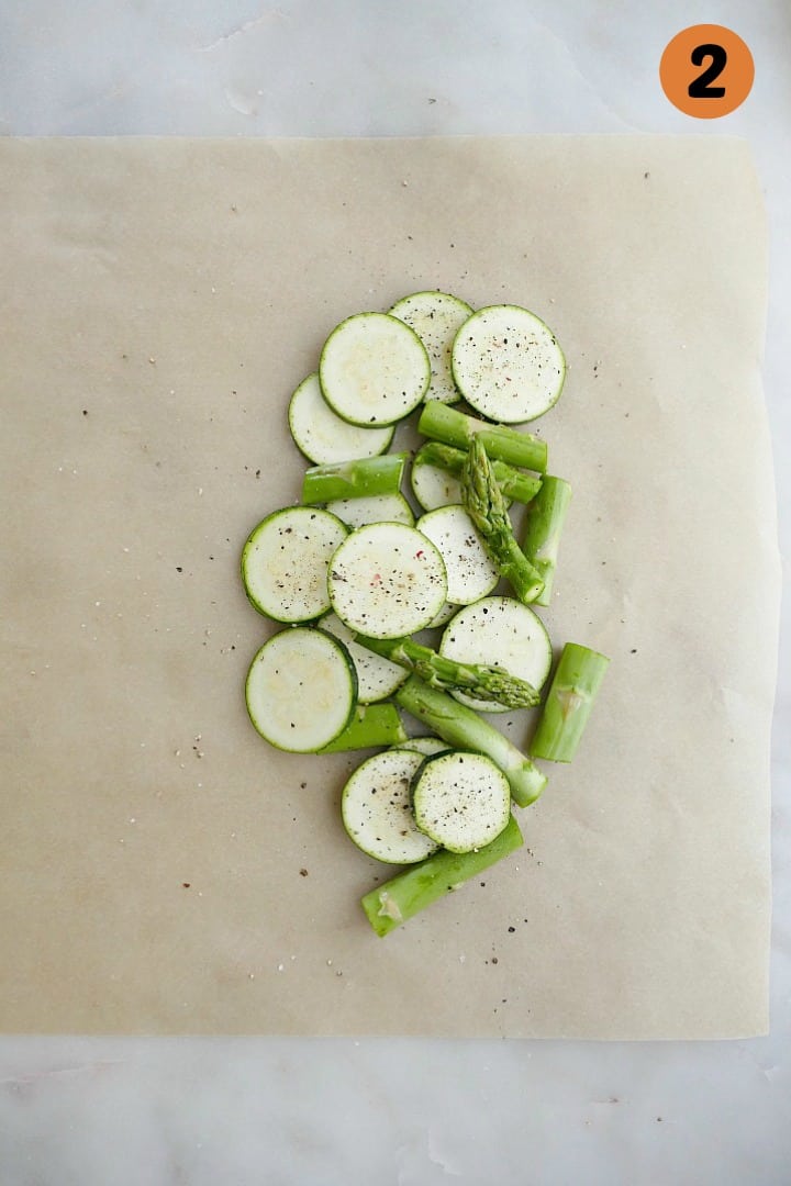 sliced zucchini and asparagus on a piece of parchment paper on a counter