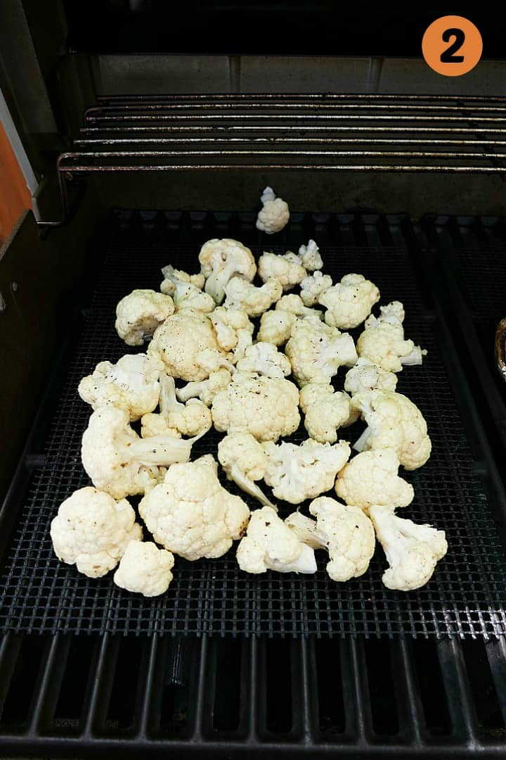 cauliflower florets on a veggie grilling mat on top of a grill