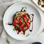 stuffed mushroom with caprese salad on a white plate on a counter
