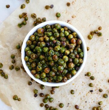 bowl of roasted peas in the center of a piece of parchment paper