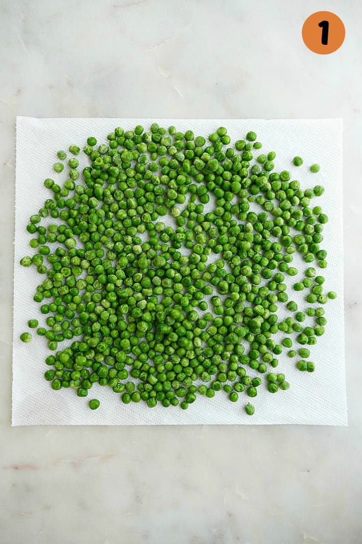 green peas spread out on a white paper towel on top of a counter