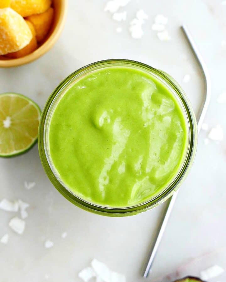 square image of an overhead shot of a green smoothie next to a straw