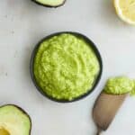 square image of avocado spread in a black bowl on a counter