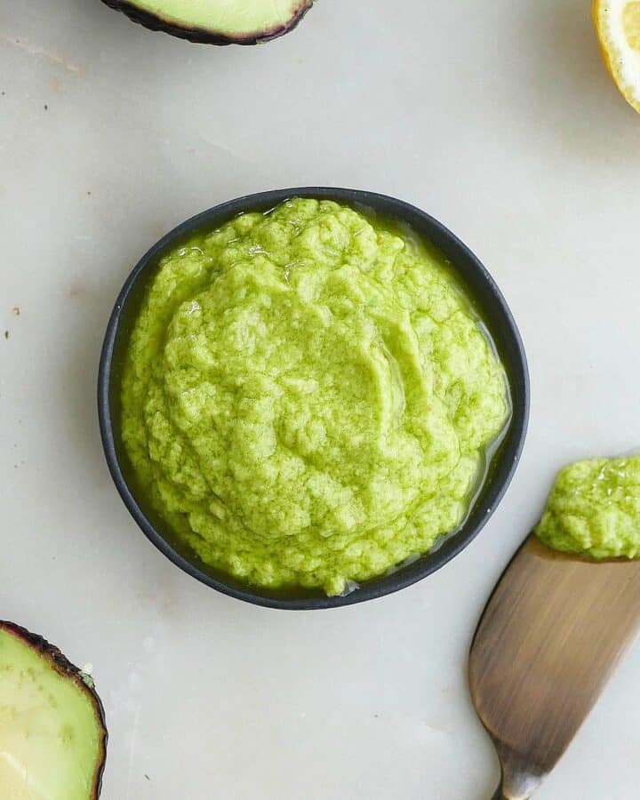 square image of avocado spread in a black bowl on a counter