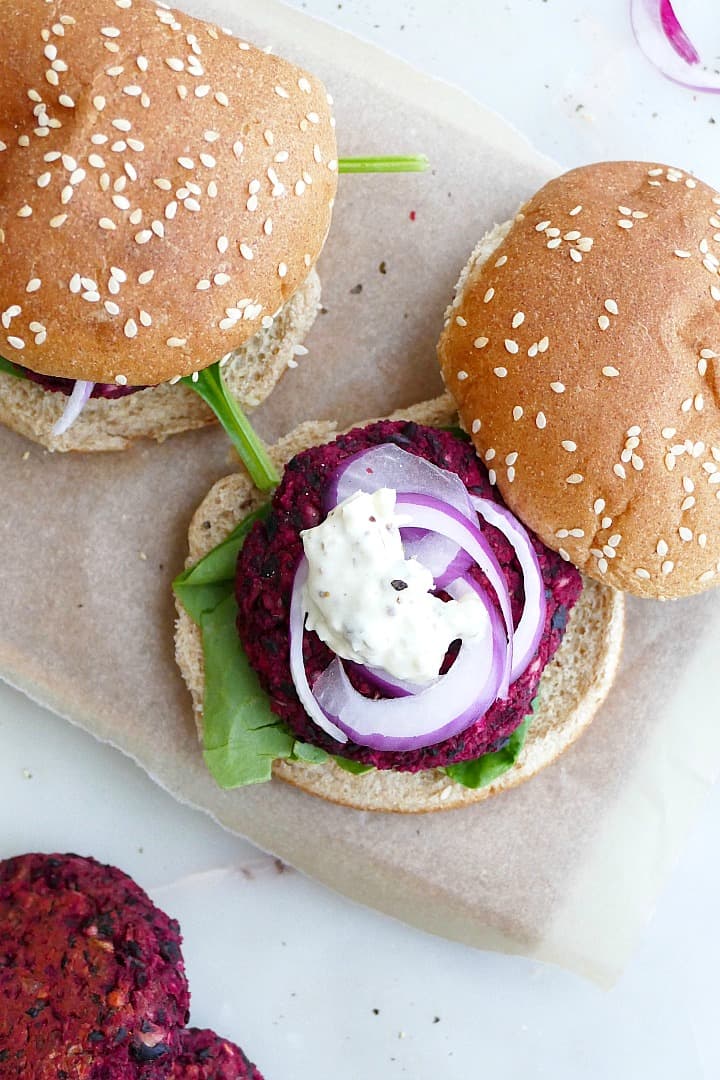 black bean beet burger on a whole wheat seeded bun with onion and mayo