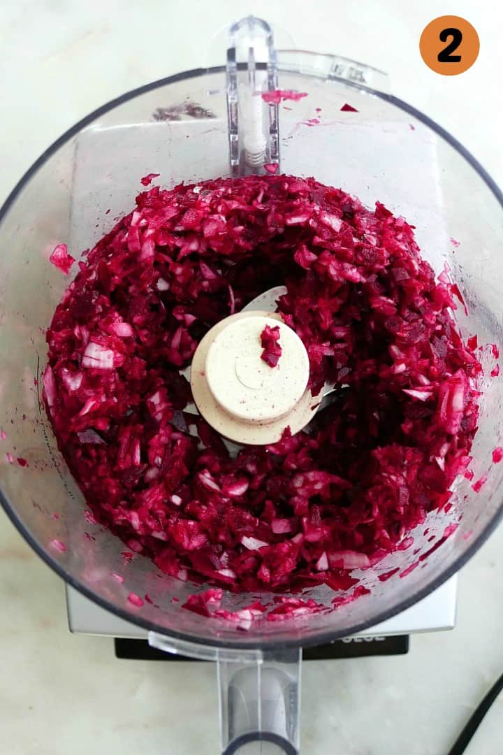 chopped onions and beets in a food processor on a counter