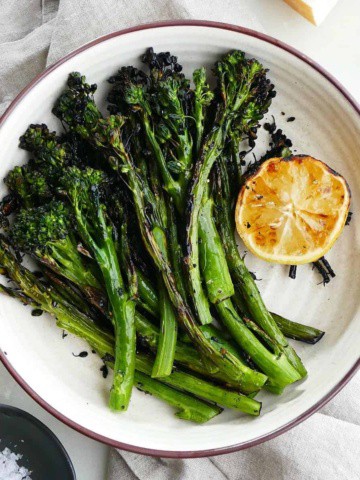 square image of grilled broccolini and lemon on top of a gray napkin