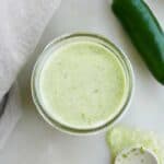 jalapeno lime dressing in a glass jar next to a napkin and spoon