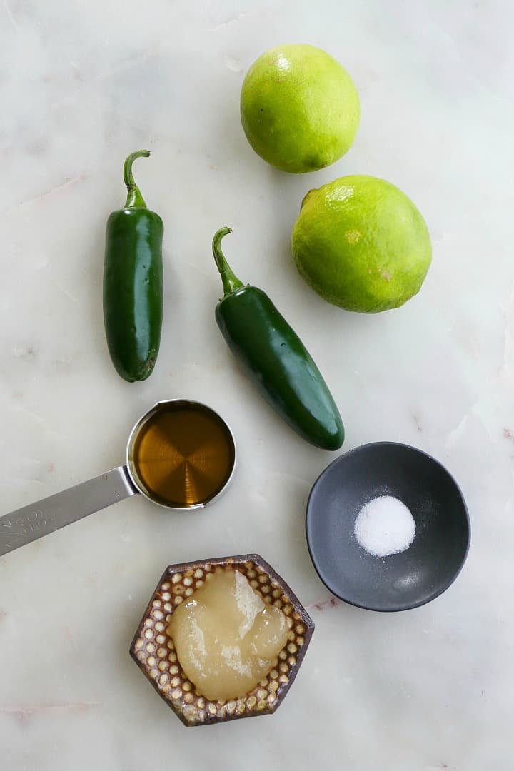 jalapenos, limes, honey, olive oil, and salt on a white counter