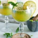 two long stem glasses with kombucha mocktails garnished with lemon slices