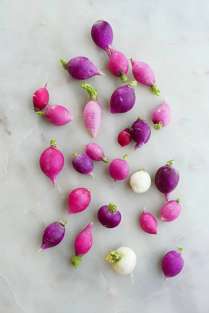 Easter Egg radishes of all different shapes and colors spread out on a counter