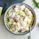radish potato salad topped with fresh dill in a gray bowl with a spoon