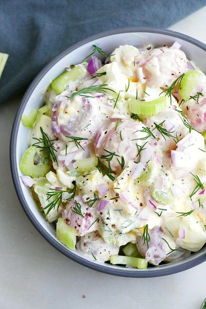 close up of radish potato salad with fresh dill in a bowl on a counter