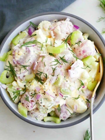 square image of radish potato salad in a bowl with a gold spoon