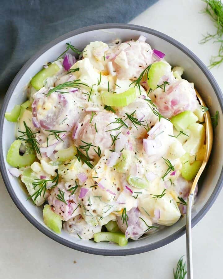 square image of radish potato salad in a bowl with a gold spoon