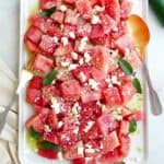 spicy watermelon salad with jalapeno dressing on a white rectangular platter