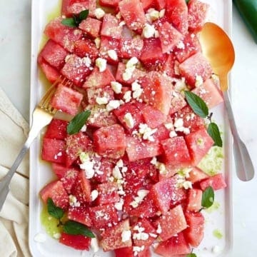 spicy watermelon salad with jalapeno dressing on a white rectangular platter