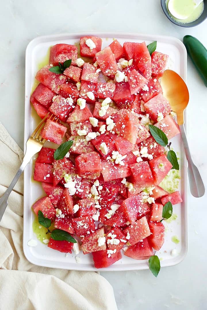 spicy watermelon salad with jalapeno lime dressing on a white rectangular platter