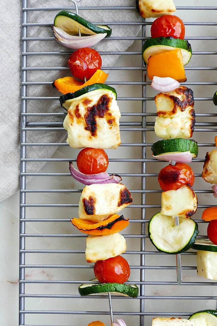 close shot of vegetable and halloumi skewers on top of a cooling rack