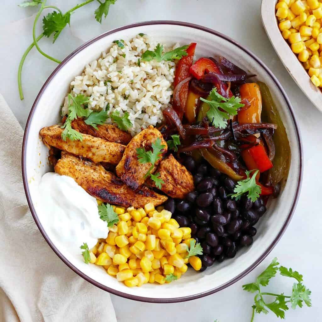 square image of chicken fajita bowl with toppings on a counter