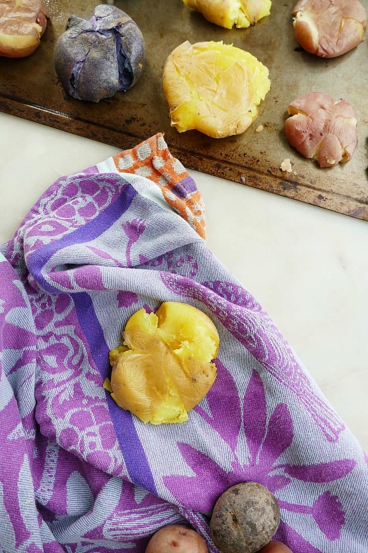 smashed potato on a clean dish towel next to a baking sheet