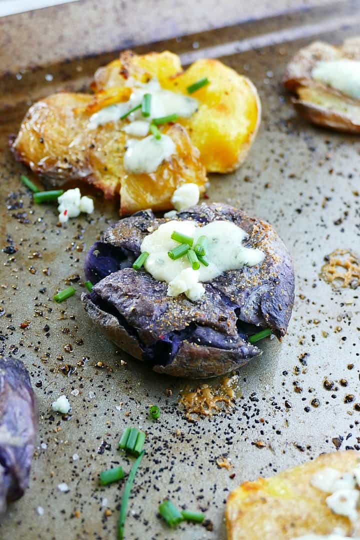 crispy smashed potatoes with blue cheese and chives on a baking sheet