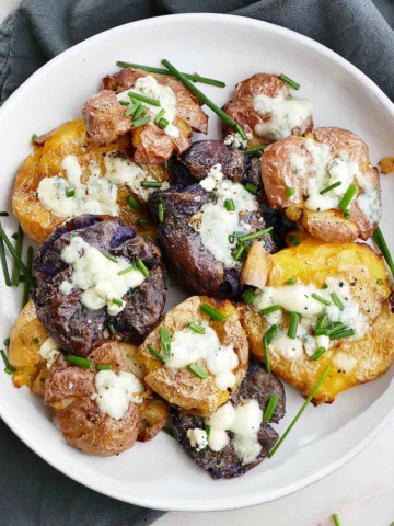 square image of a plate of crispy smashed potatoes with blue cheese and chives