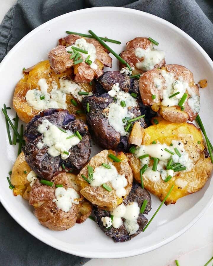 square image of a plate of crispy smashed potatoes with blue cheese and chives